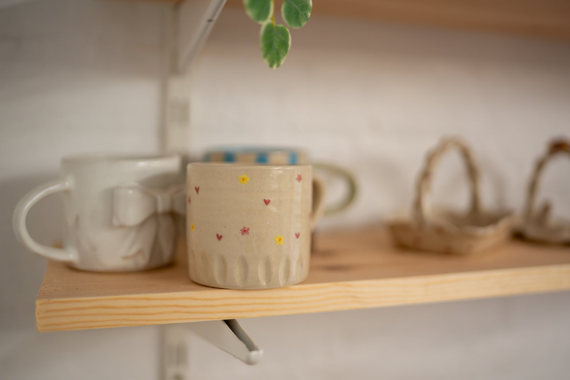 Two ceramic mugs on a wooden shelf with a blurred background