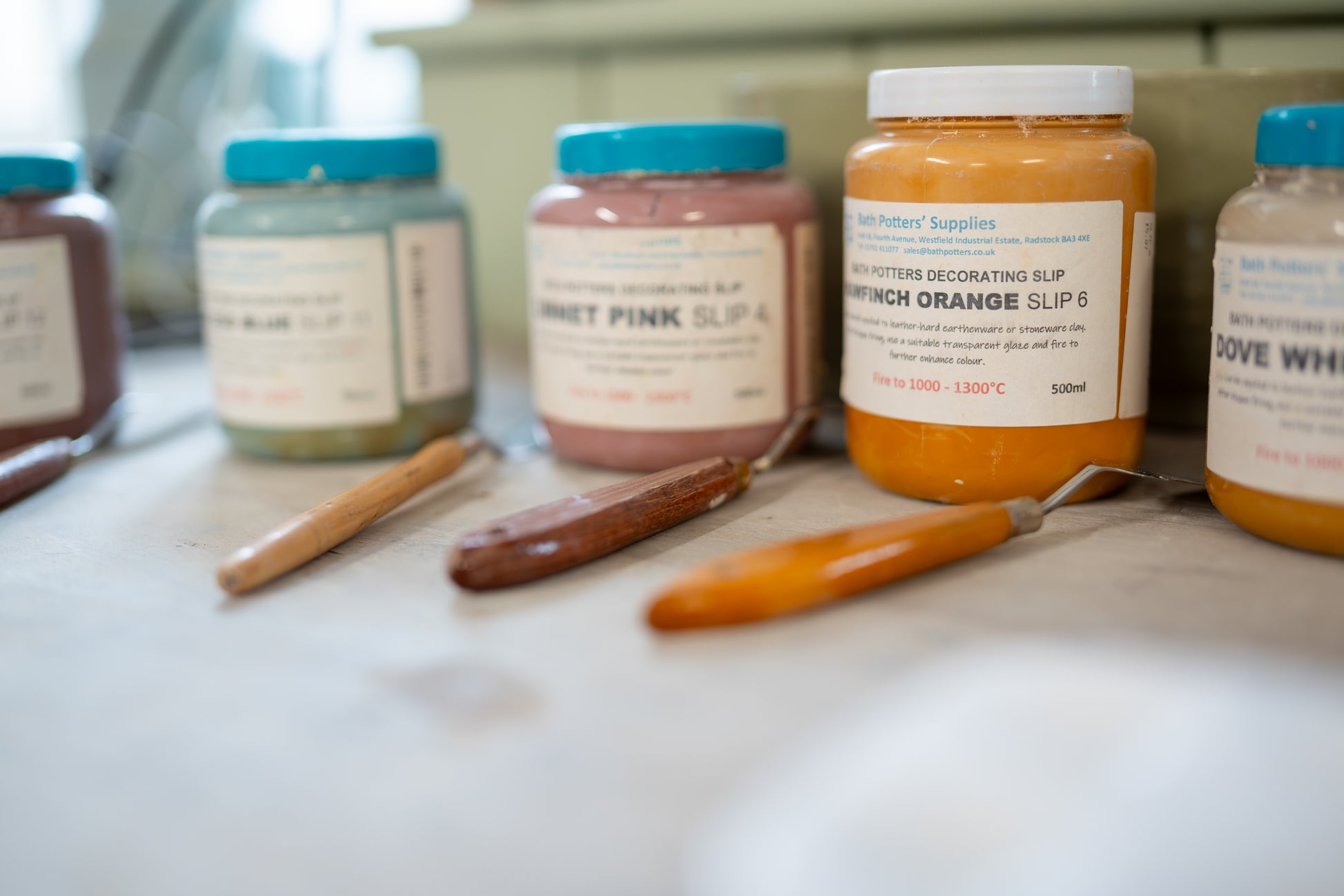 Jars of different colored slips on a table with tools