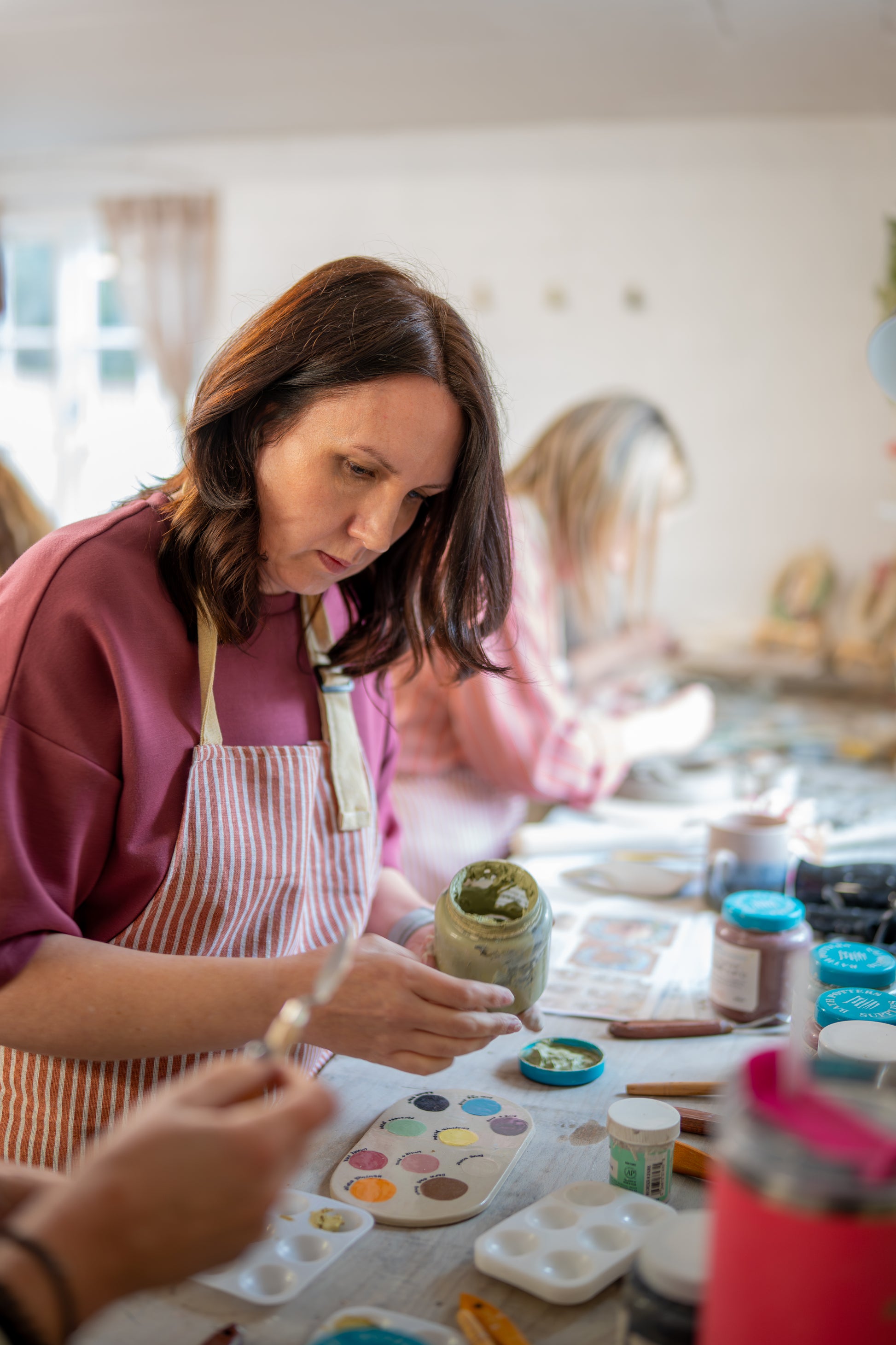 Woman painting with underglazes in a studio setting